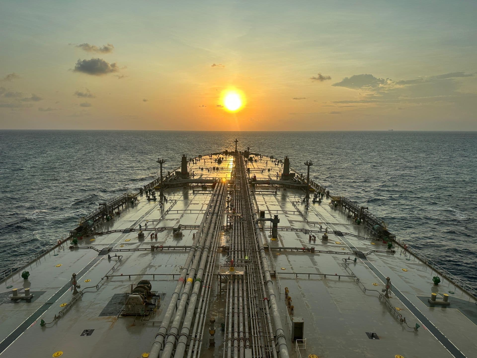 Oil tanker sailing across the open sea at sunset