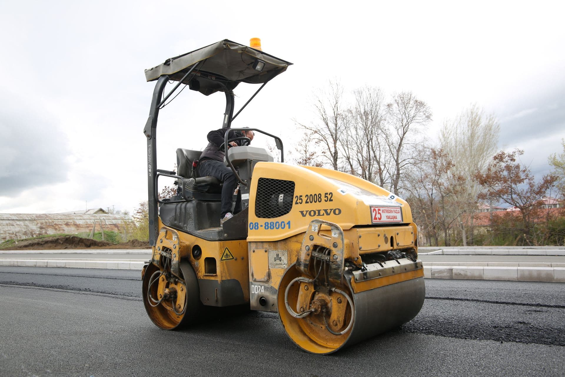 Road roller compacting fresh asphalt during road construction
