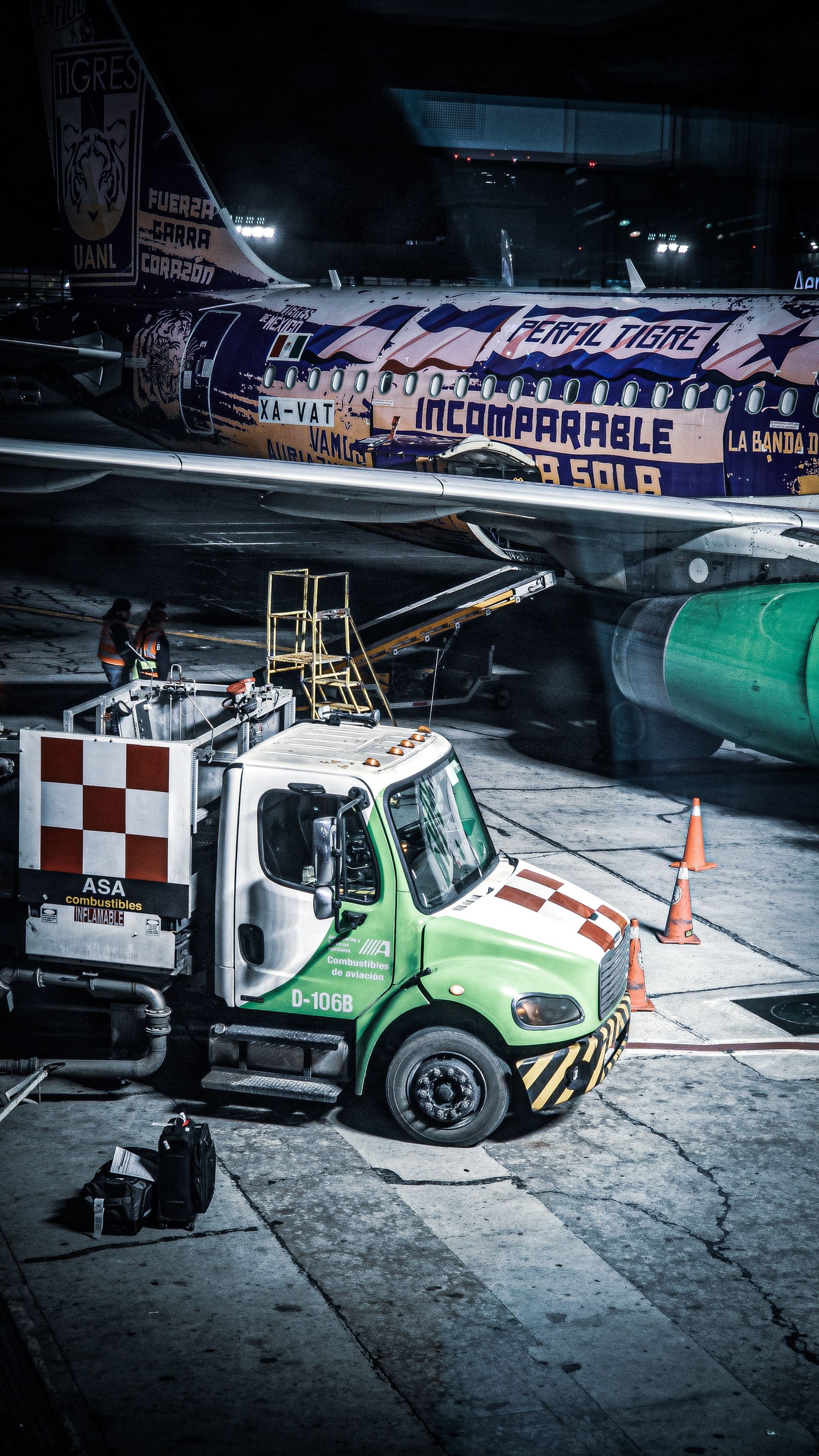 Commercial aircraft being refuelled on the tarmac at night